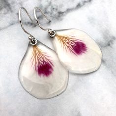 pair of white and red flower earrings on marble background