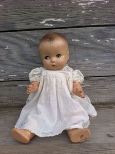 a small doll sitting on top of a wooden floor next to a wood plank wall