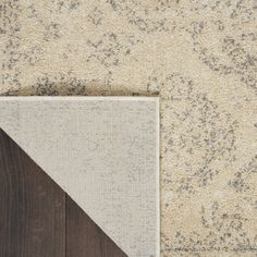 an area rug that has been placed on top of a wooden floor with a gray and white color scheme