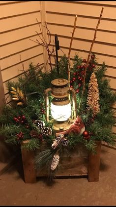 a lantern surrounded by evergreens and pine cones on a wooden crate with christmas decorations