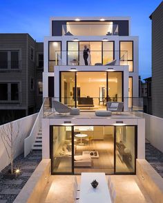 a modern house with an outdoor patio and dining table in the foreground at dusk