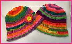 two colorful crocheted hats with a flower on the front and one has a button at the center