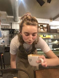 a woman is pouring something into a cup