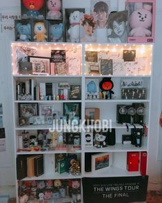 a book shelf filled with lots of books next to a wall covered in pictures and lights