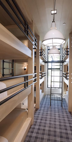 a long hallway with bunk beds and lights on the ceiling is lit by a round light fixture