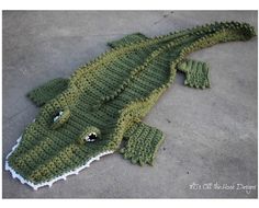 a crocheted alligator laying on the ground