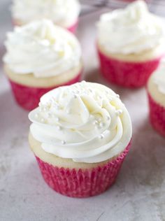 cupcakes with white frosting sitting on a table