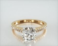 a yellow gold engagement ring with diamonds on the band and a round cut diamond in the center