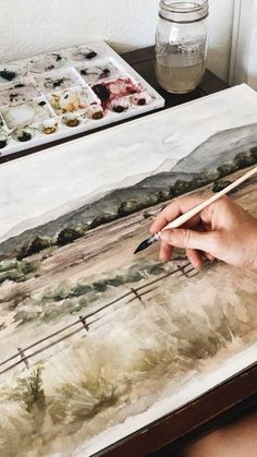 a person is painting on an easel with watercolors