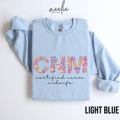 Fun and colorful floral letters spell out CNM on this cute sweatshirt for all the hardworking Certified Nurse Midwives out there!  Your coworkers and your patients will love this cozy and stylish sweatshirt designed to keep you comfortable during those long workdays while showcasing your passion for your profession.  Whether you're working hard in the hospital or spending time with friends and family, this sweatshirt will keep you warm, comfortable, and stylish.   DETAILS This classic, unisex, heavy-blend crewneck sweatshirt is super comfortable! Made from 50% cotton, 50% polyester, this combination will fit like a well-loved favorite. The collar is ribbed knit, so it retains its shape even after washing, and there are no itchy side seams. As with any online product, the colors may look sl Spring Cotton Sweatshirt With Lettering, Blue Cotton Sweatshirt With Lettering, Blue Text Print Sweatshirt For Spring, Multicolor Letter Print Relaxed Fit Sweatshirt, Multicolor Letter Print Sweatshirt Relaxed Fit, Blue Long Sleeve T-shirt With Name Print, Blue Crew Neck Sweatshirt With Name Print, Multicolor Cotton Sweatshirt With Letter Print, Blue Sweatshirt With Letter Embroidery For Spring