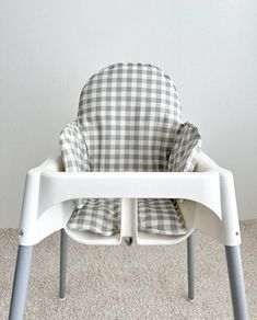 a white and gray checkered highchair with pillows on it's seat