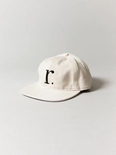 a white hat with the letter i on it, sitting against a gray background and black lettering