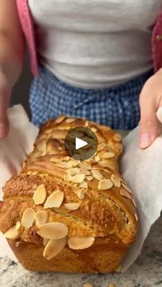 a loaf of bread sitting on top of a counter next to a person holding a piece of paper