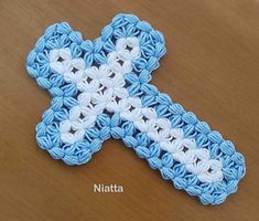 a crocheted blue and white cross sitting on top of a wooden table