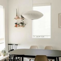 a dining room table with four chairs and a lamp hanging from the ceiling above it