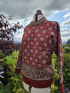 This beautiful, cosy jumper is knitted on my vintage hand-frame machine. All my knitwear is individually produced and finished by hand. This Corrachree design is available in a variety of colourways and sizes. Photo shows Blaze Red in size Medium: the main colour is a rich red with a fleck natural contrast and a border of brown, reds and natural white. Wool is very breathable, which means less frequent washing. However, when it does need to be washed, it should be hand washed in tepid water, giv