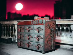 a red and black cabinet sitting on top of a roof next to a building at night