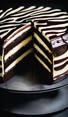 a chocolate cake with white and brown frosting on a black plate, cut in half