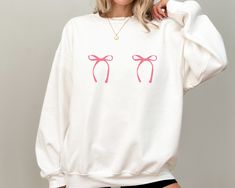 - Pink Bows Gildan crewneck sweatshirt. Perfect to wear on everyday occasions. Great to give as a gift.  - Pictured is a White Gildan crewneck sweatshirt.  Designed on the front is a pair of pink bows that are side by side. - Available in four colors; Navy, Sand, Sport Grey, and White - Ideal for any situation, a unisex heavy blend crewneck sweatshirt is pure comfort. These garments are made from polyester and cotton. This combination helps designs come out looking fresh and beautiful. The collar is ribbed knit, so it retains its shape even after washing.  - The classic fit along with the crew neckline deliver a comfy wearing experience with a clean-cut style. Meanwhile, the double-needle stitching at the shoulder, armhole, neck, waistband, and cuff seams add top-tier durability.  - Made u Cute White Crew Neck Sweater, White Crew Neck Sweatshirt For Gift, Cute Relaxed Fit Hoodie With Crew Neck, White Crew Neck Sweatshirt As Gift, Cute Crew Neck Sweatshirt For Gift, Cute White Crew Neck Sweatshirt, Casual Crew Neck Sweatshirt As Gift, Casual White Sweatshirt As Gift, Cute White Crew Neck Hoodie