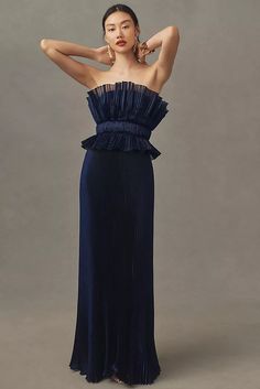 a woman in a blue dress posing for the camera with her hands on her head