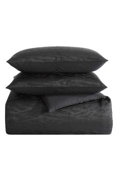 three pillows stacked on top of each other with one black pillow and the other dark