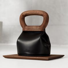 a wooden handle on top of a black leather bag that is sitting on a table