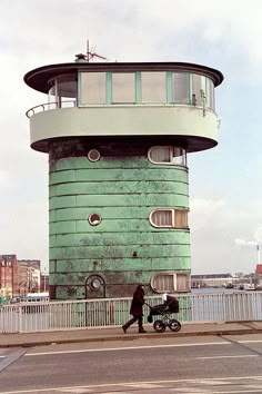 a person walking across a bridge with a stroller in front of a tall building