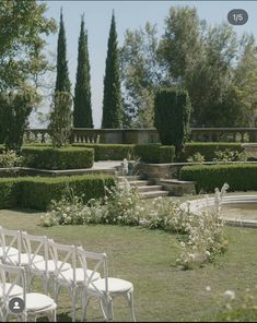 white chairs are set up in the middle of a garden