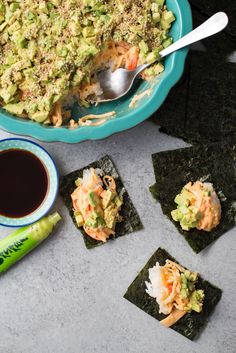 sushi rolls with avocado, carrots and other toppings next to a bowl of dipping sauce