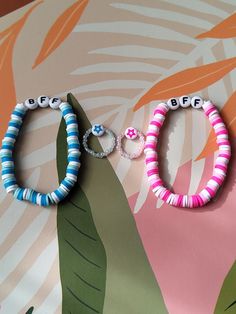 two bracelets that say bebe and are on top of a palm leaf background