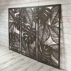 a metal screen with leaves on it in a room next to a wooden panel wall