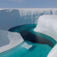 an iceberg with blue water and snow on the ground, in the middle of nowhere