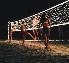 people are playing volleyball on the beach at night