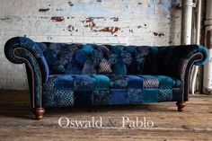 a blue couch sitting on top of a wooden floor next to a white brick wall