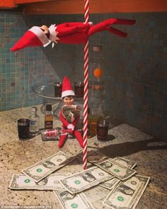 an elf is sitting on top of money in the kitchen with a candy cane sticking out of it