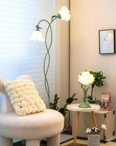 a white chair sitting next to a table with flowers on it in a living room