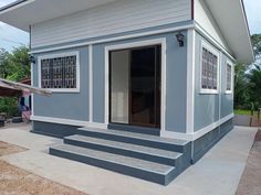 a small house with steps leading to the front door and windows on each side of the porch