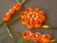 three orange flowers with pearls on them