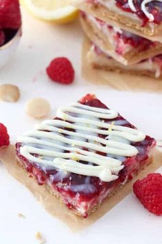 lemon raspberry magic bars with white chocolate drizzled on top and fresh raspberries