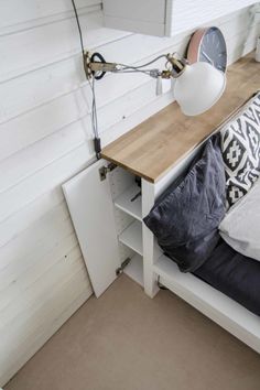 a bed with a wooden headboard next to a white wall and a clock on it