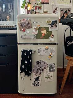 an old fashioned refrigerator is covered in magnets and pictures on the front, along with other items