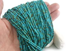 a hand holding a strand of turquoise beads