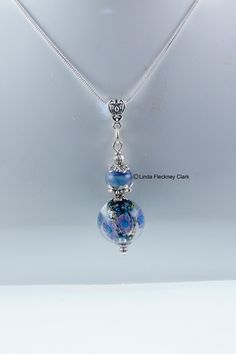 "I have created this one-of-a-kind 'Blue Chrysanthemum' pendant necklace from a round lampwork and dichroic glass bead with glass chrysanthemum flowers, matching lampwork glass spacer bead, silver plated pewter and brass spacer bead, bead caps, jewellery wire, bale and snake chain necklace with lobster clasp. Alt Text Necklace made  from a round lampwork and dichroic glass bead with glass chrysanthemum flowers, matching lampwork glass spacer bead, silver plated pewter and brass spacer bead, bead Blue Chrysanthemum, Jewellery Wire, Lampwork Necklace, Snake Chain Necklace, Chrysanthemum Flower, Dichroic Glass, Bead Caps, Handmade Necklace, Necklace Handmade