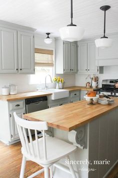 a kitchen with white cabinets and wooden counter tops, two chairs in front of the island