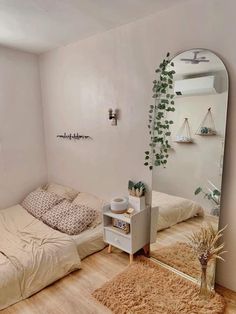 a bedroom with a bed, mirror and plant on the floor in front of it