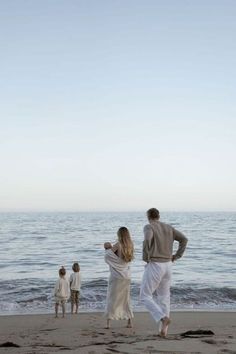 a group of people standing on top of a sandy beach next to the ocean,