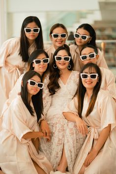 a group of women wearing white sunglasses pose for a photo