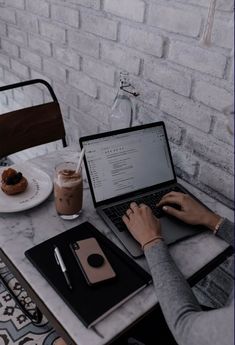 a person sitting at a table with a laptop and cup of coffee in front of them