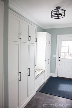 an empty entryway with white cabinets and blue rug on the floor in front of it