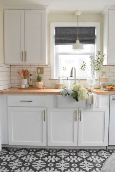 a kitchen with white cabinets and black and white tile on the floor is pictured in this image